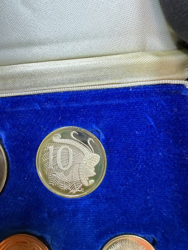Coin with a profile design on a blue cushion